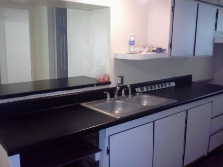 kitchen and counter top pass through a window and breakfast nook is to the left of the photographer, the refrigerator and stove is directly across from sink and counter tops.